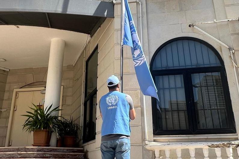 A UN staff is is lowering the UN flag at a UN building in Yemen