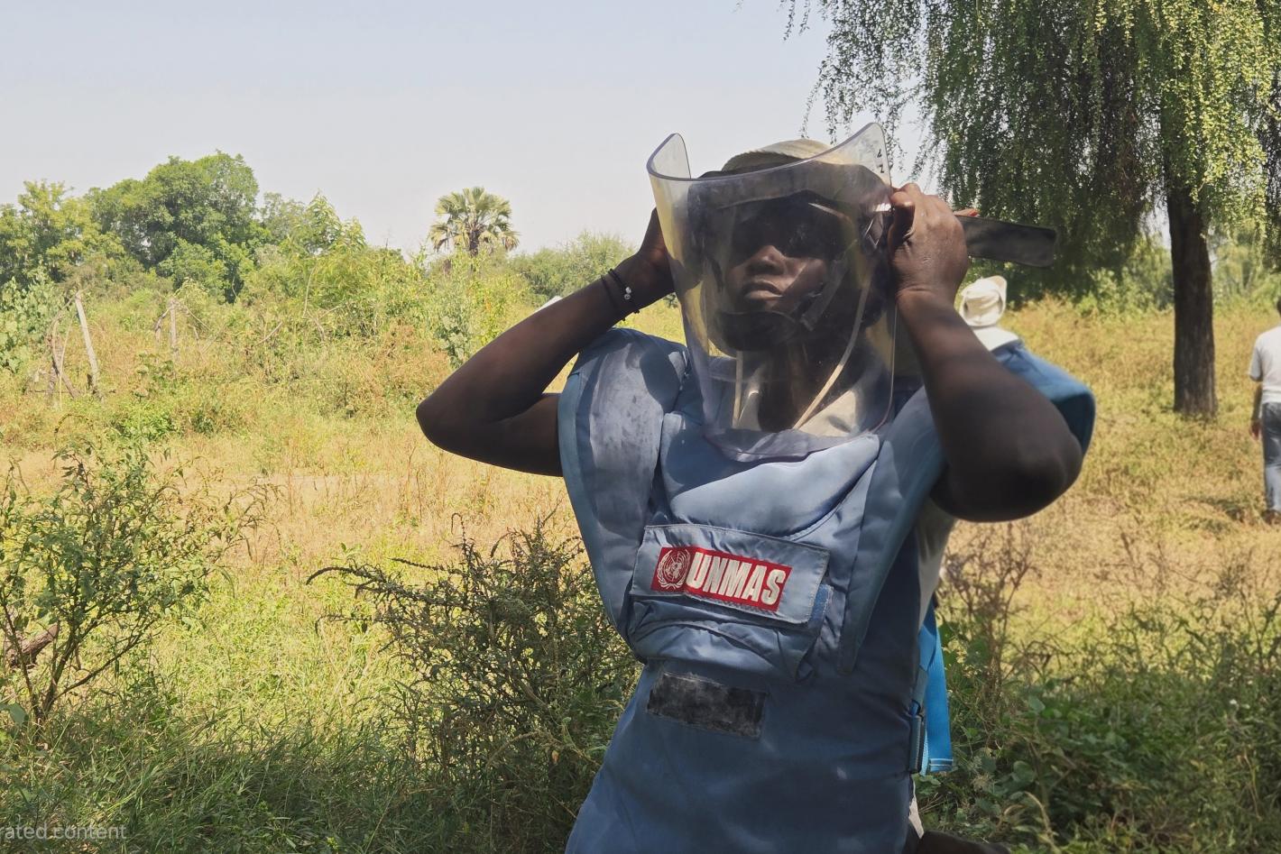 a woman deminer is putting on a protective mask